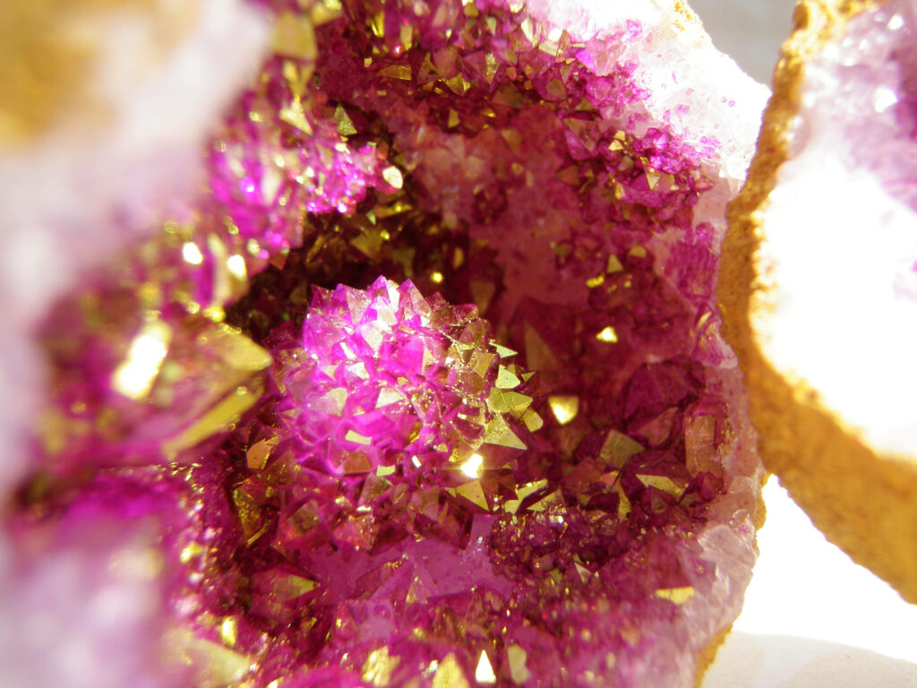 Close-up of vibrant pink and gold amethyst crystals with sparkling geometric formations wallpaper