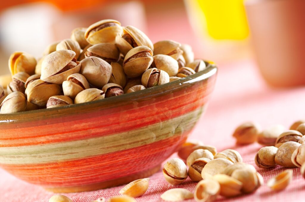 Vibrant Pistachio Bowl on Colorful Striped Plate – Warm Wallpaper