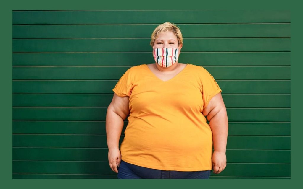 Plus-size person with short blonde hair wearing bright yellow shirt and colorful striped mask Wallpaper