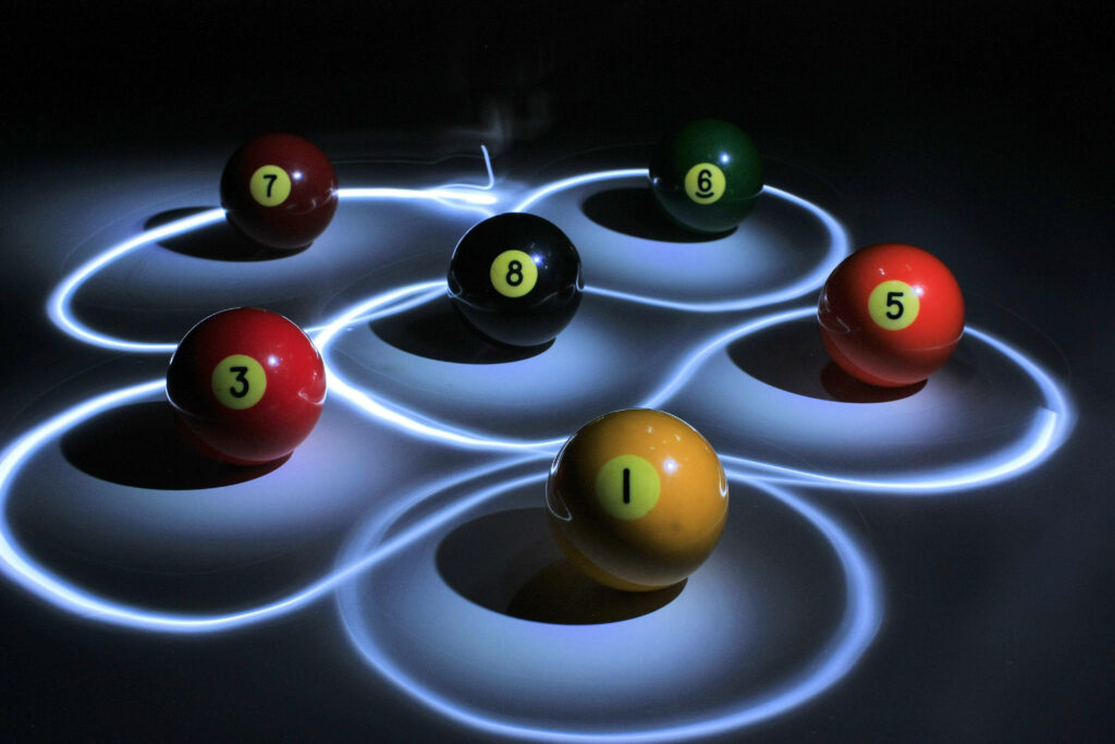 Vibrant Pool Balls 1-8 with Light Trails on Dark Background Wallpaper