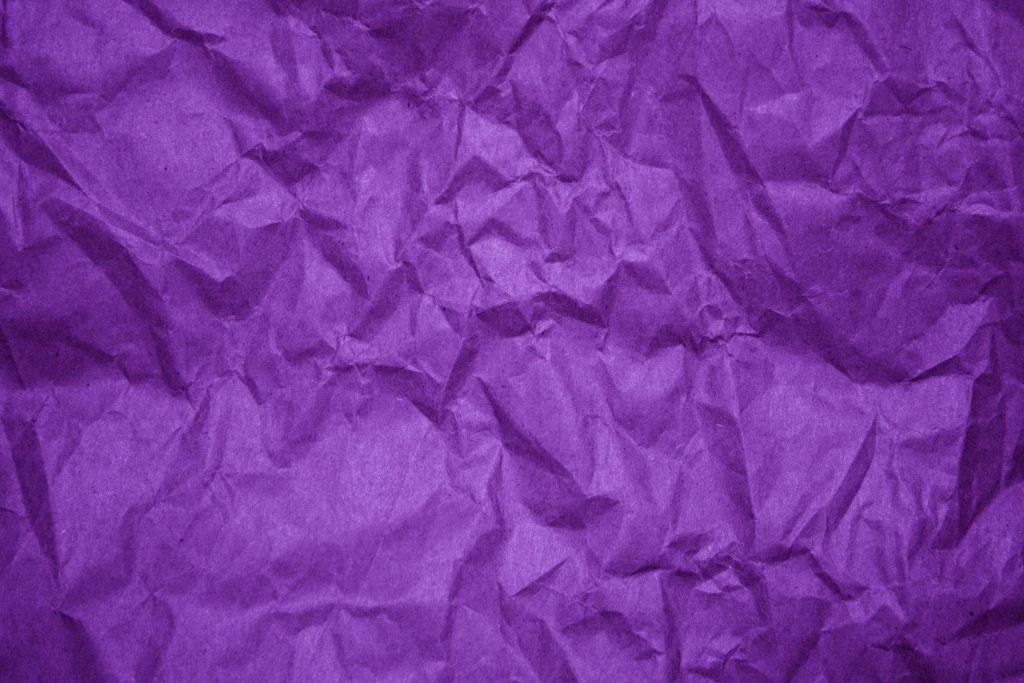 Vibrant purple crumpled paper with deep violet folds and dramatic shadows textured wallpaper background