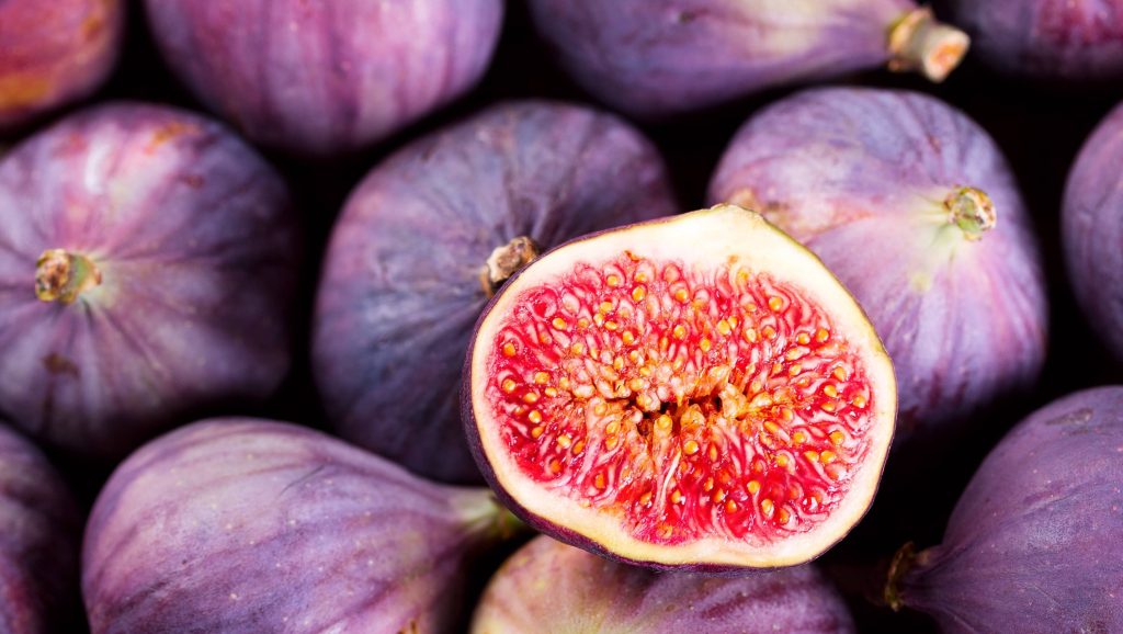 Close-up vibrant purple figs with sliced bright red interior showcasing juicy texture wallpaper