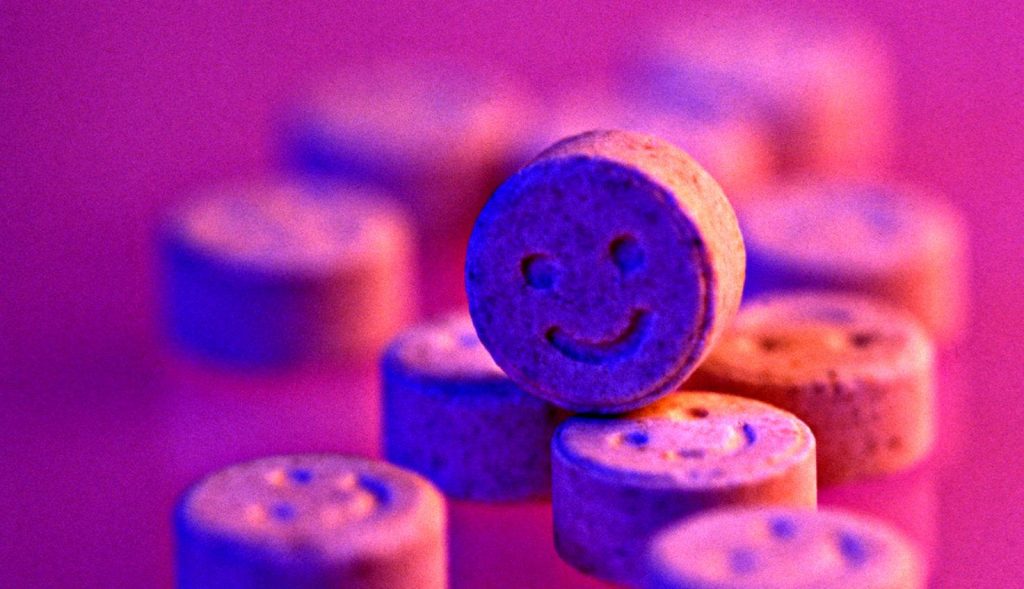Macro close-up of textured smiley face tablets in vibrant purple neon lighting HD wallpaper
