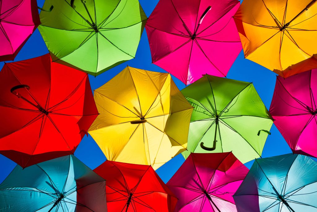 Colorful translucent umbrellas against blue sky vibrant rainbow aesthetic wallpaper background