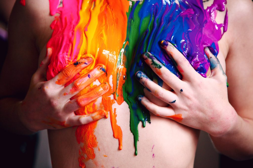 Close-up of torso with vibrant dripping rainbow body paint for Pride desktop wallpaper background