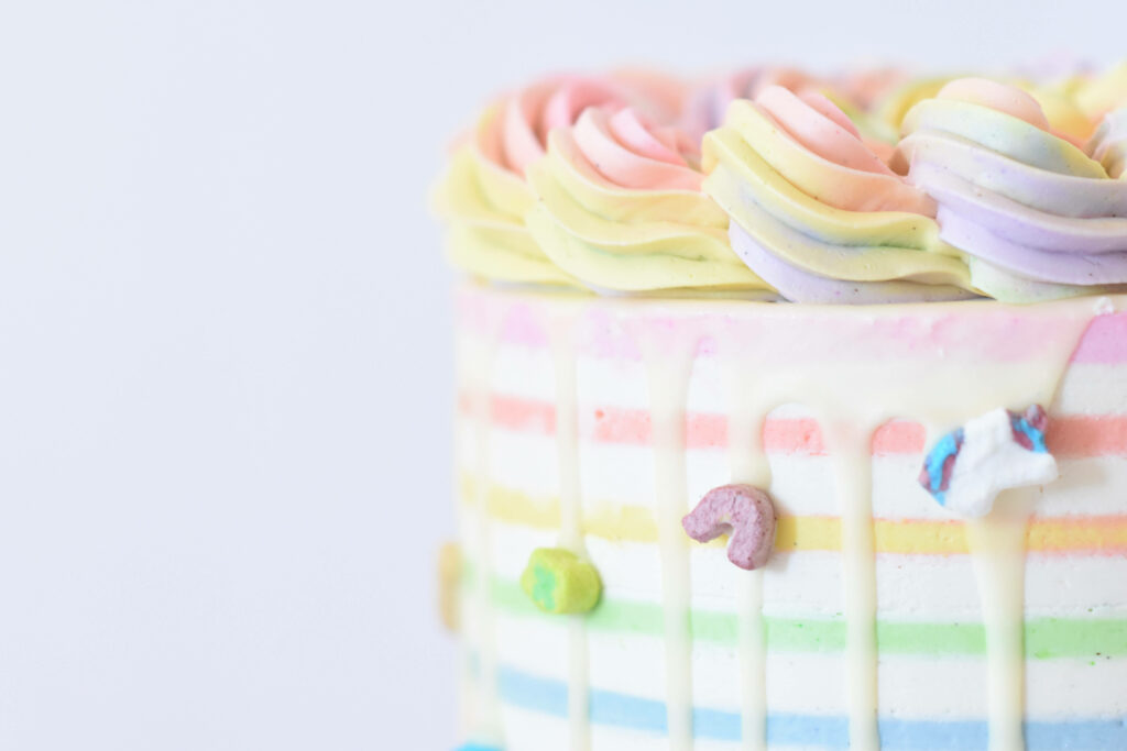 Vibrant pastel rainbow cake wallpaper with creamy drips swirled icing and colorful cereal toppings