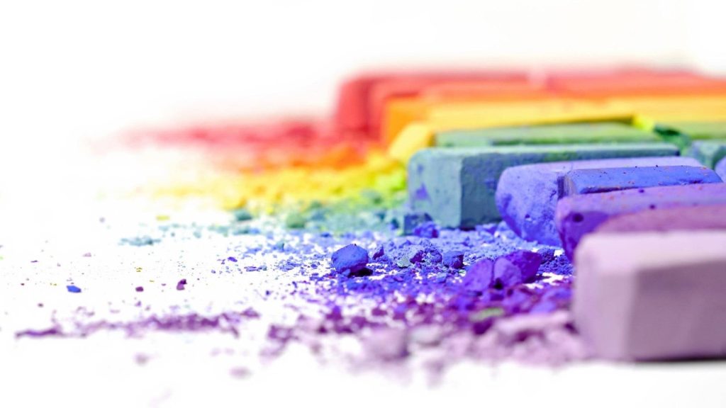 Macro photo of vibrant rainbow chalk pastels from sticks to powder on white background desktop wallpaper