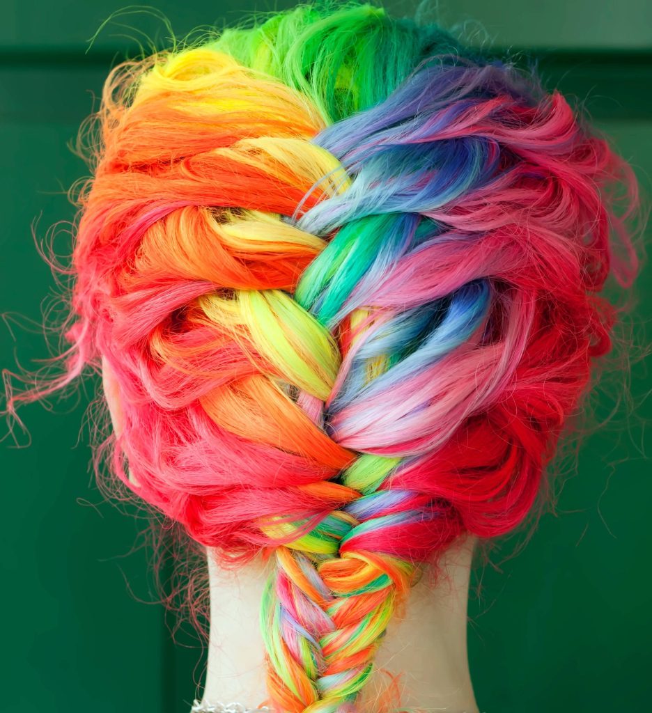Vibrant rainbow fishtail braid hair against dark green background colorful artistic wallpaper