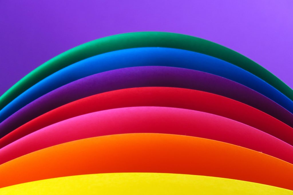 Vibrant rainbow paper layers in concentric curves on smooth purple background desktop wallpaper