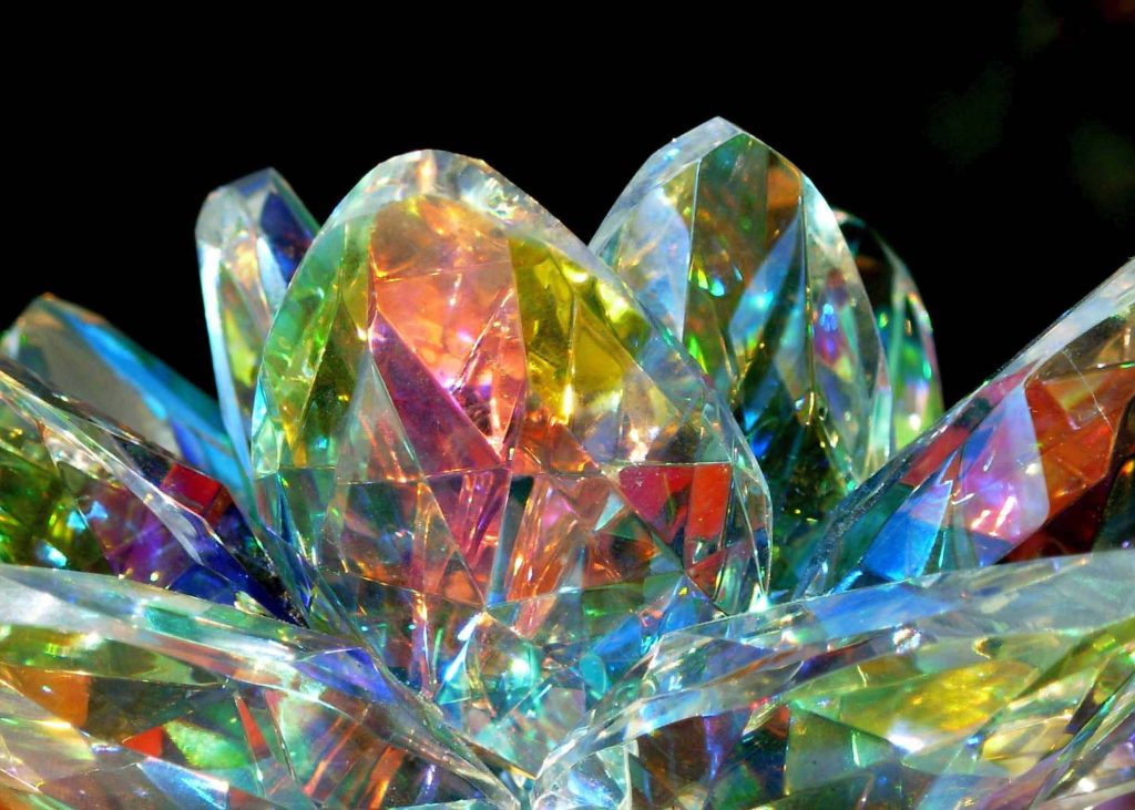 Close-up of a multifaceted glass lotus flower crystal with vibrant rainbow light refractions on dark background Wallpaper