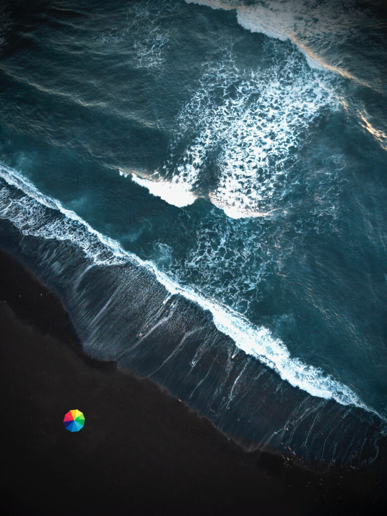 Vibrant Rainbow Umbrella on Dark Beach – Stunning iPhone Wallpaper