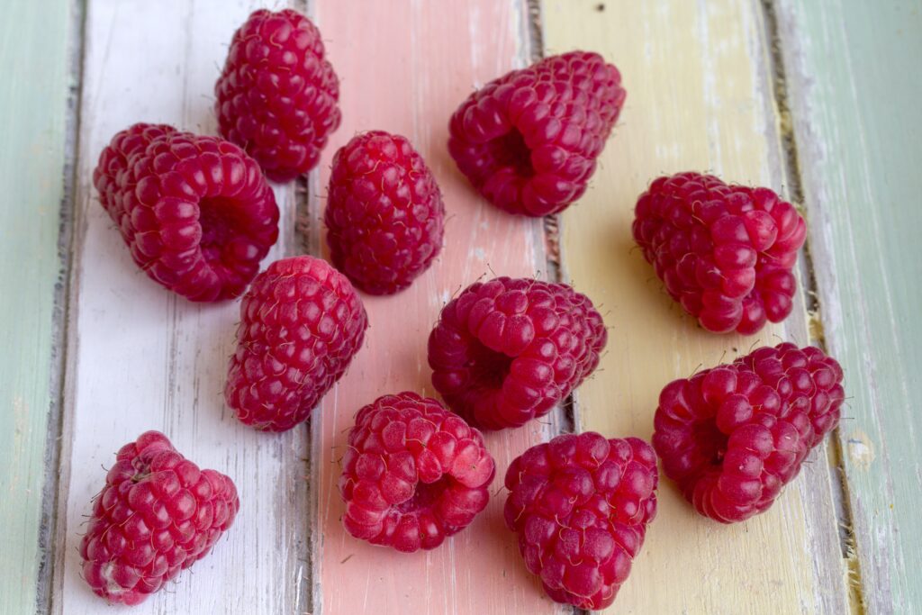 Vibrant Raspberry Wallpaper Background on Pastel Wooden Table
