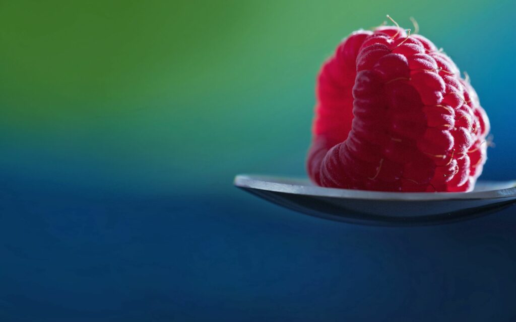 Vibrant Raspberry Close-Up on Spoon - Soft Green and Blue Wallpaper