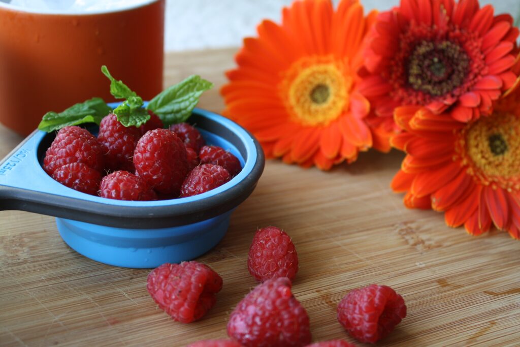 Colorful Wallpaper: Ripe Raspberries in Blue Cup with Orange Flowers