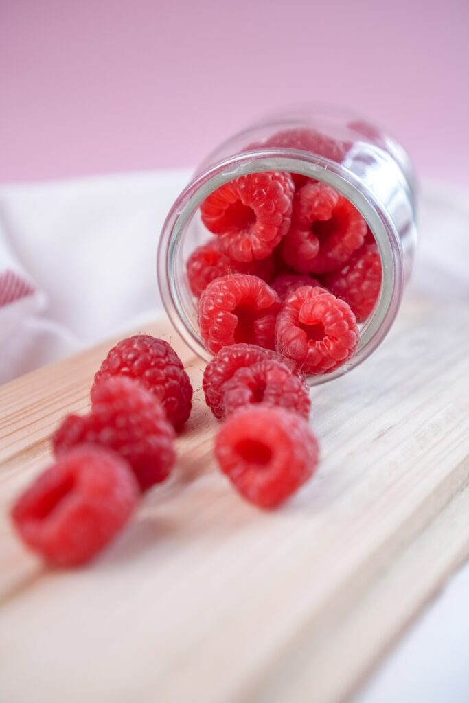 Fresh Raspberries Wallpaper: Vibrant Jar on Wooden Surface