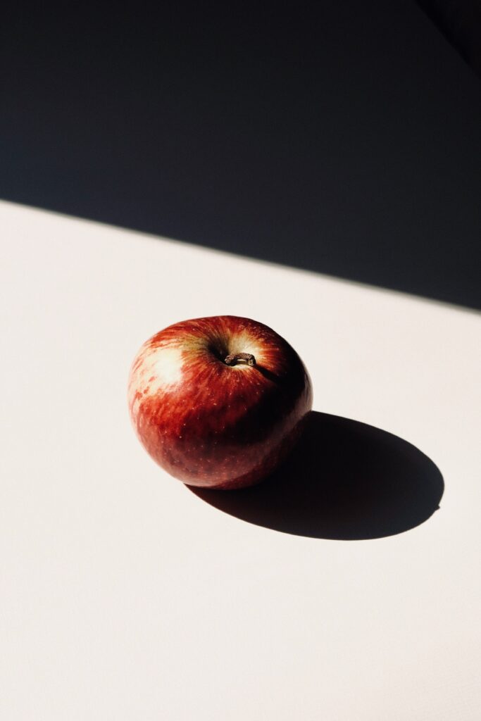 Vibrant Red Apple Wallpaper: Bright Light & Shadow on Clean Surface