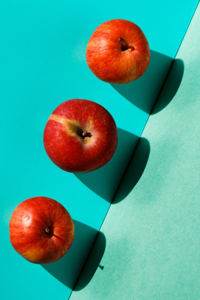Fresh Red Apples on Vibrant Blue-Green Wallpaper Background
