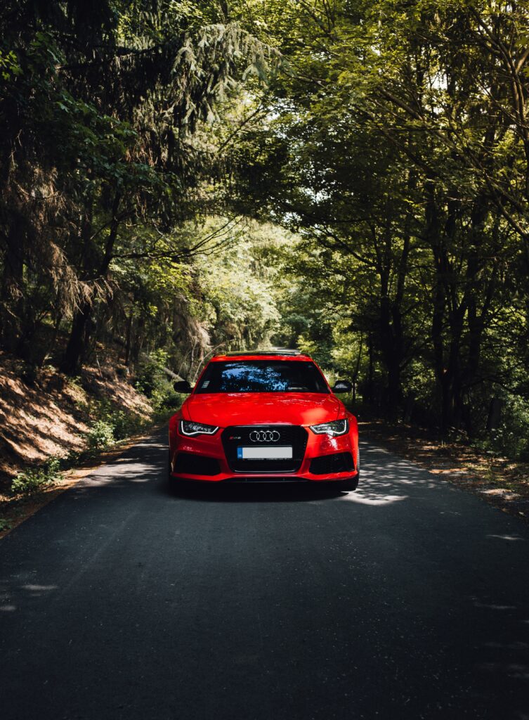 Red Audi Wallpaper: Vibrant Car in Lush Forest Background