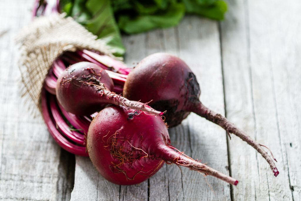 Vibrant Red Beetroots with Greens on Rustic Wood Wallpaper Background
