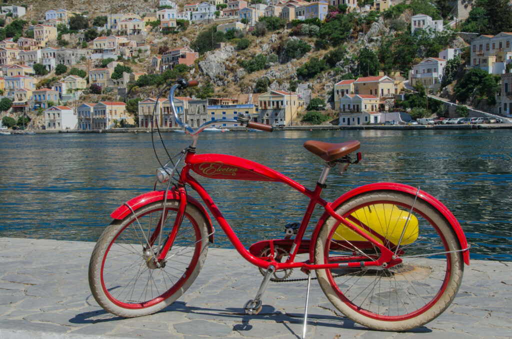Vibrant red bike parked by calm lake with colorful hillside houses in serene lakeside scene wallpaper