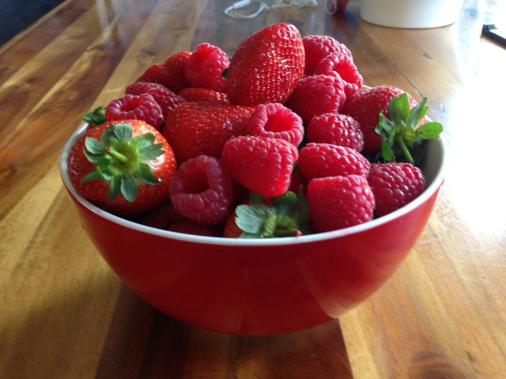 Vibrant Red Bowl of Fresh Berries on Wooden Table – Wallpaper Background