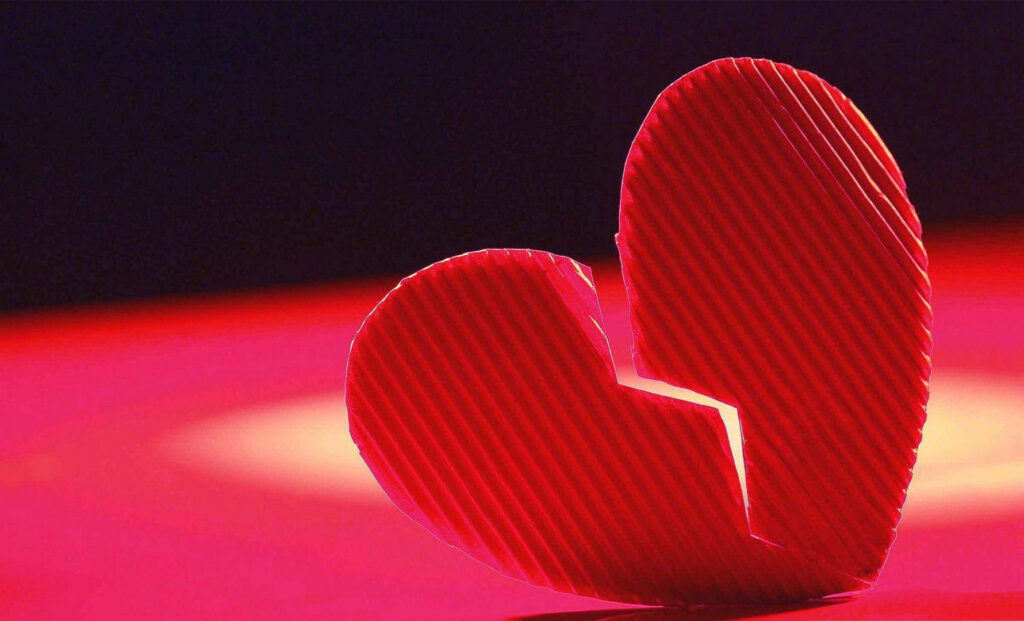 Red broken heart made from corrugated cardboard on pink purple gradient background wallpaper