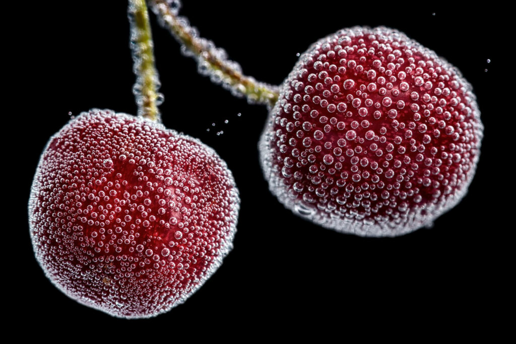 Close-up of two red cherries with sparkling air bubbles on black background high definition fruit wallpaper