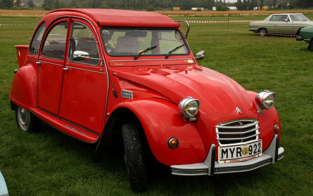 Vibrant Red Citroën 2CV Wallpaper in Lush Green Setting