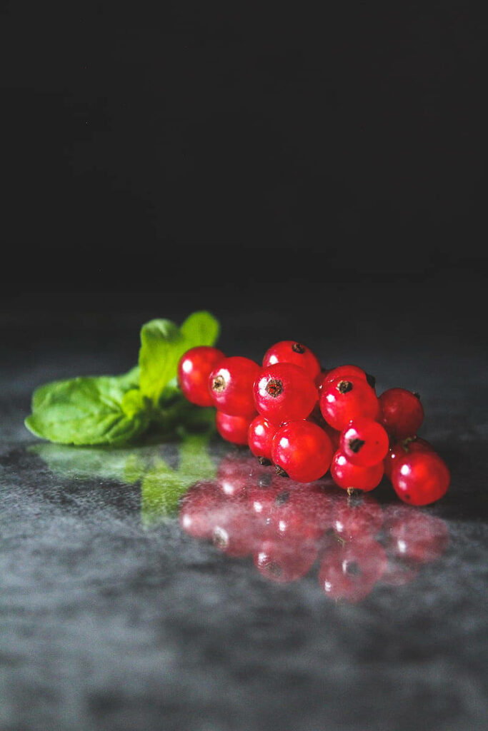 Vibrant Red Currant Wallpaper: Lush Green Leaves on Dark Surface