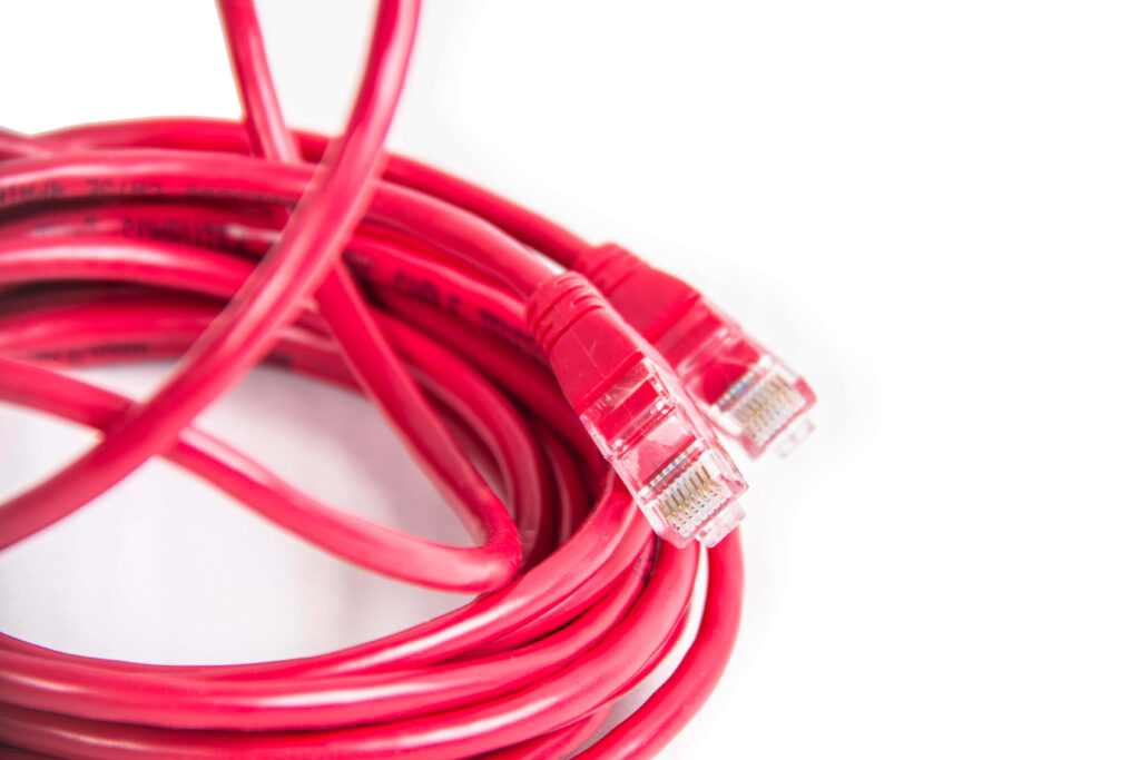 Coiled red Ethernet cable with clear connectors on white background technology wallpaper