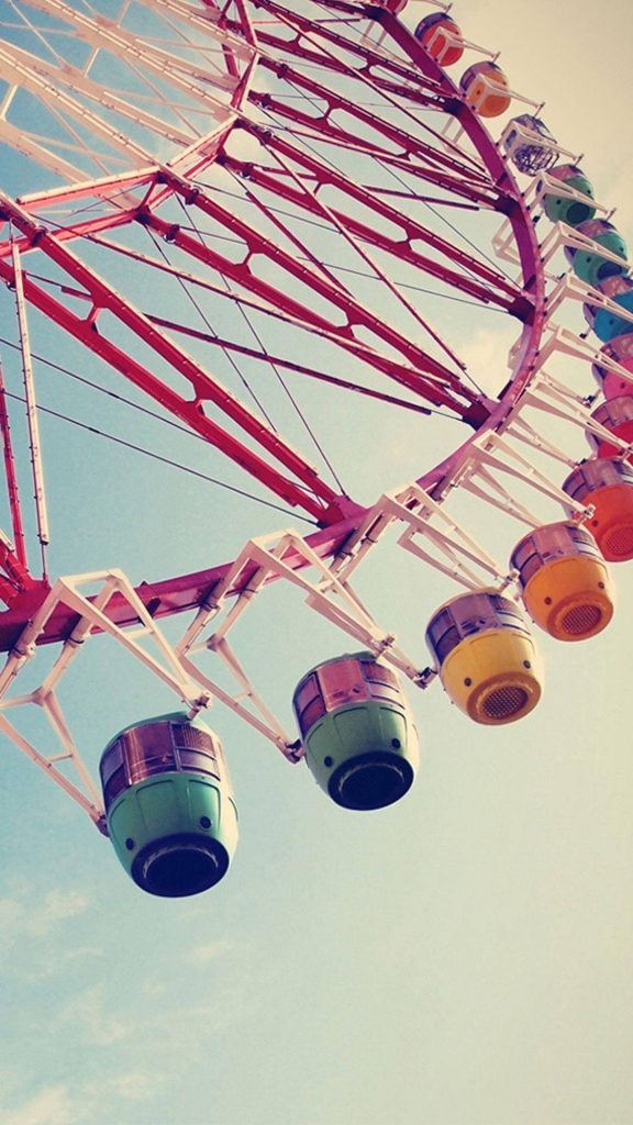 Vibrant red Ferris wheel with colorful gondolas under clear blue sky cheerful fair wallpaper