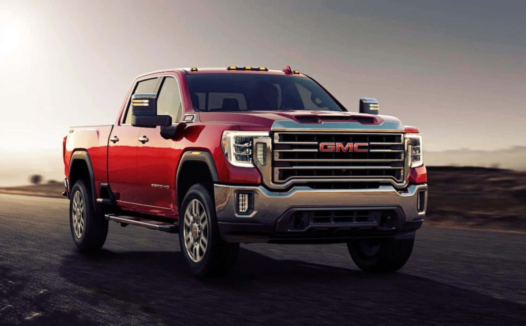 Red GMC Sierra HD truck at sunset with bold chrome grille and rugged heavy-duty design Wallpaper