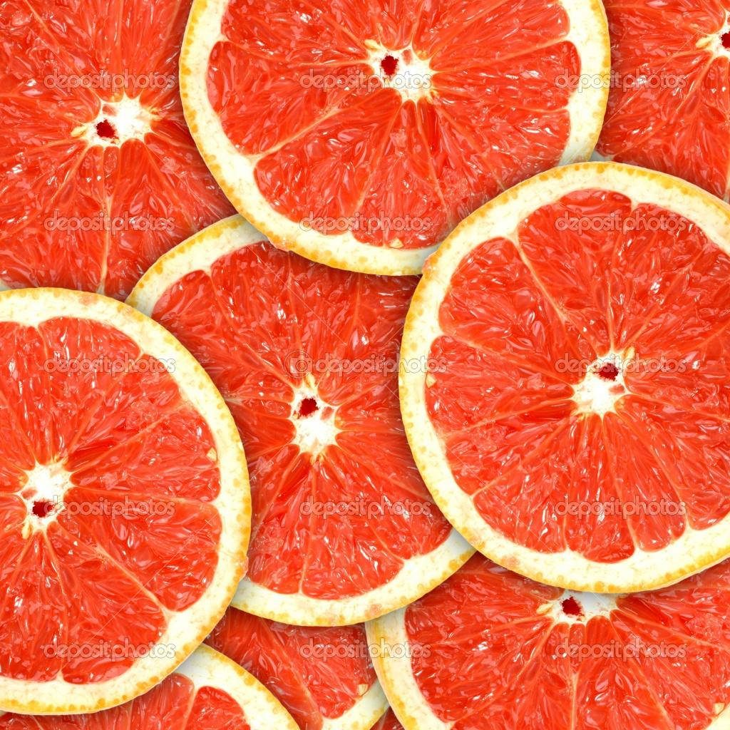 Vibrant red grapefruit slices overlapping in detailed high-resolution citrus pattern wallpaper background