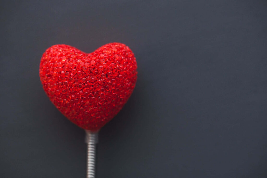 Vibrant Red Heart-Shaped Lollipop on Dark Wallpaper Background