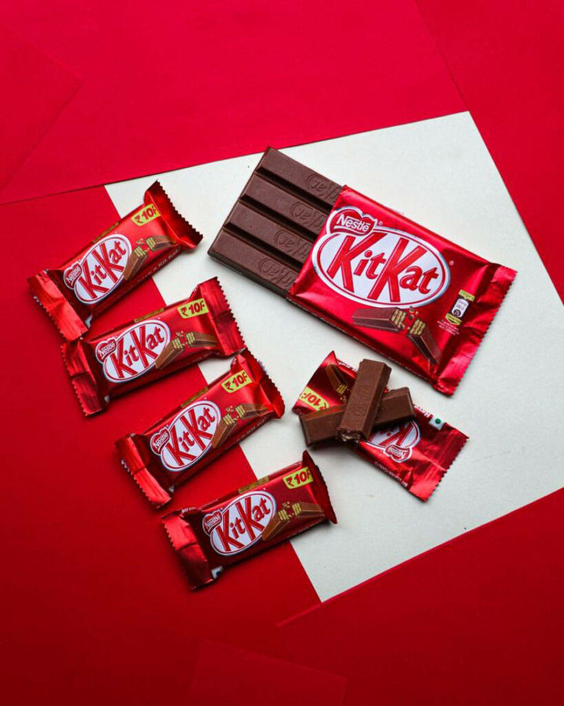 Vibrant red Kit-Kat chocolates wrapped and unwrapped on bold geometric red and white background Wallpaper