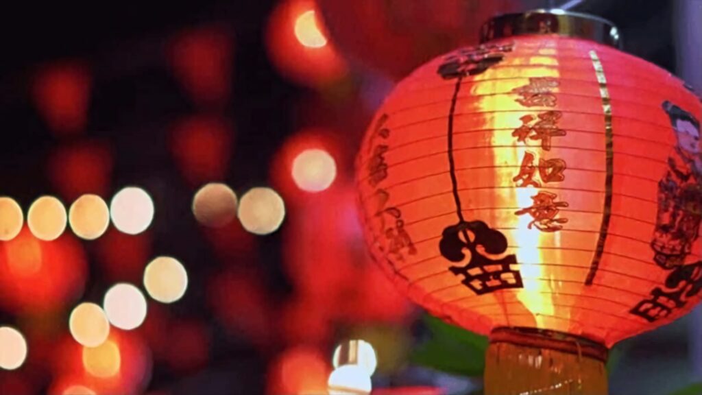 Vibrant red Chinese New Year lantern glowing warmly with festive decorations background Wallpaper