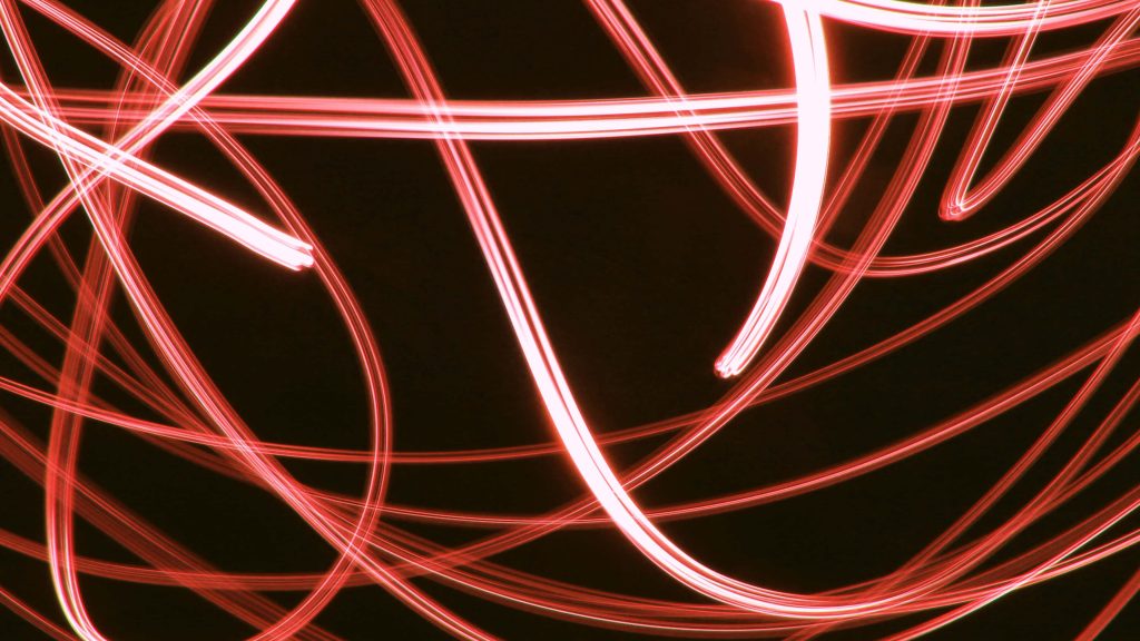 Vibrant red neon light painting with dynamic glowing trails on a black background wallpaper