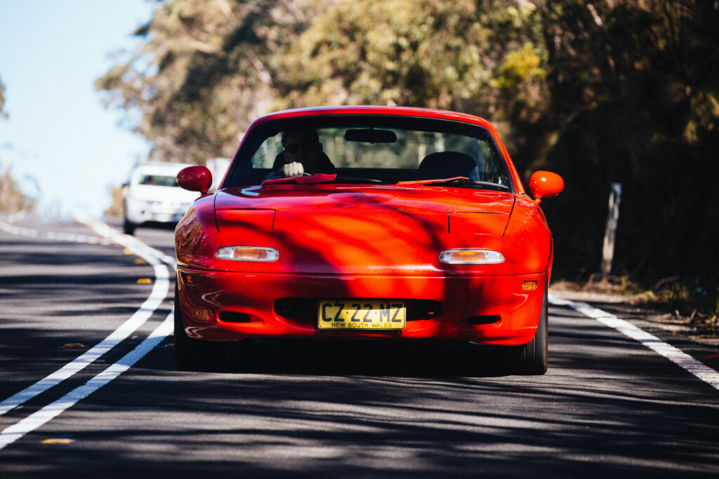 Vibrant Red Mazda RX-7: Front View on Scenic Road Wallpaper