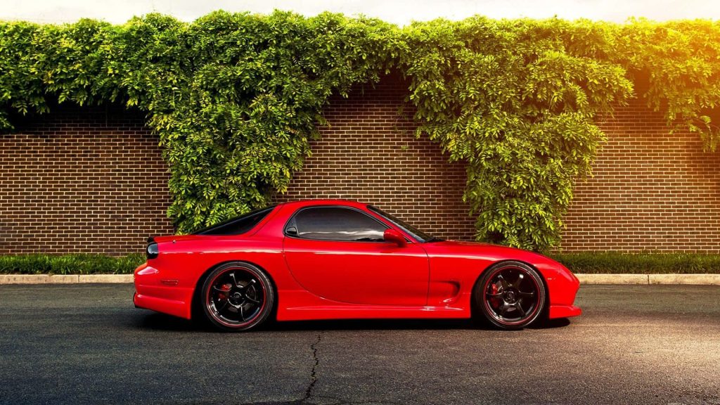 Red Mazda RX-7 FD sports car parked by brick wall with green vines in golden sunlight wallpaper