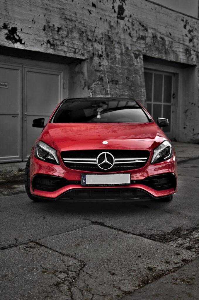 Vibrant Red Mercedes: Modern Elegance Against Urban Gray Background Wallpaper