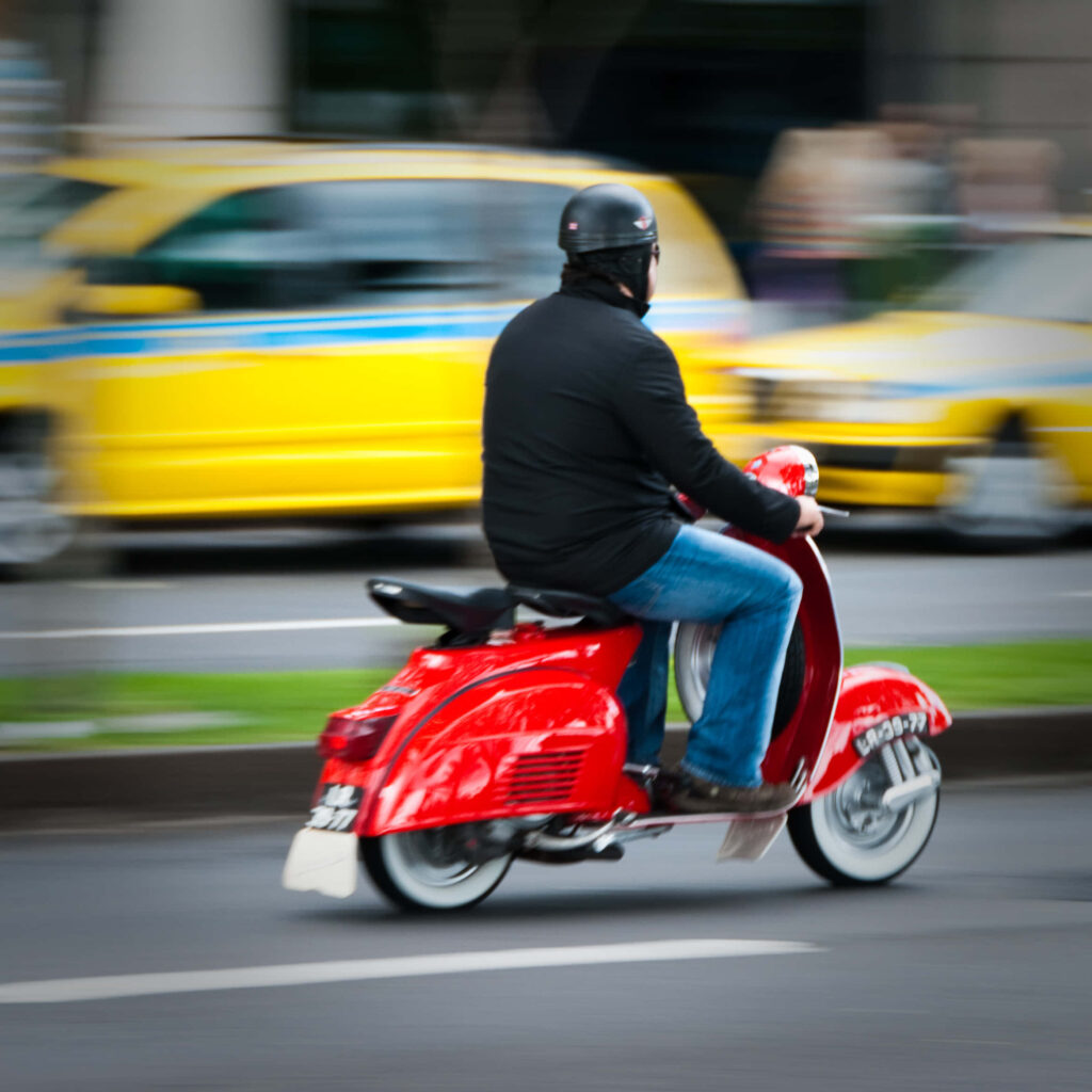 Vibrant Red Moped Ride: Urban Motion Blur Wallpaper Background