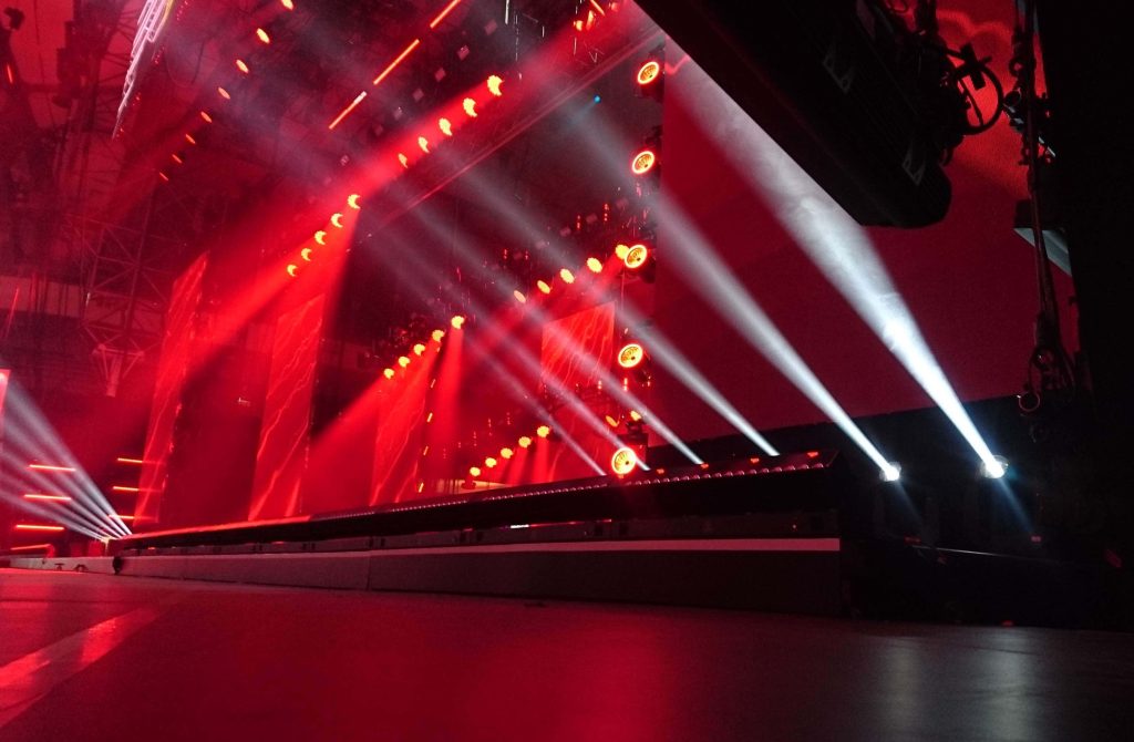 Vibrant red concert stage with white spotlights dramatic low-angle live music wallpaper background