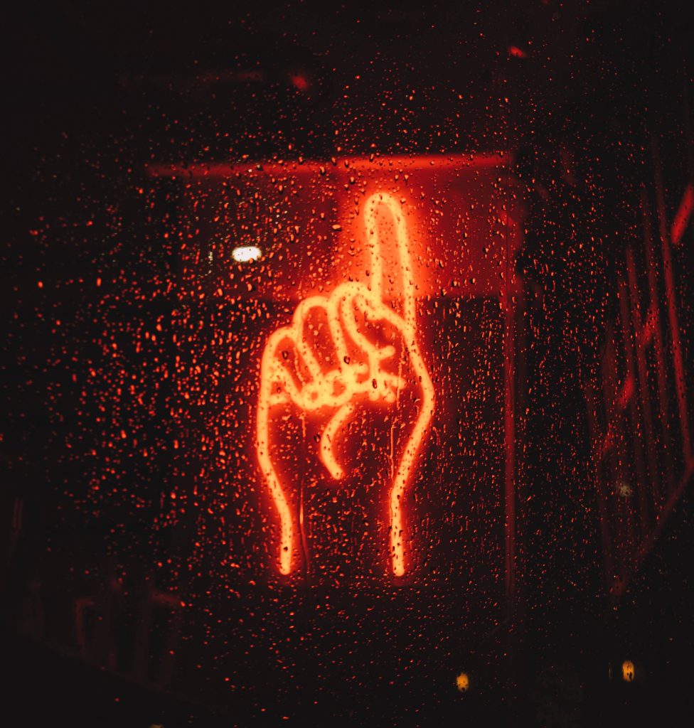 Red neon index finger sign glowing through rain-streaked window with moody urban light diffusion Wallpaper