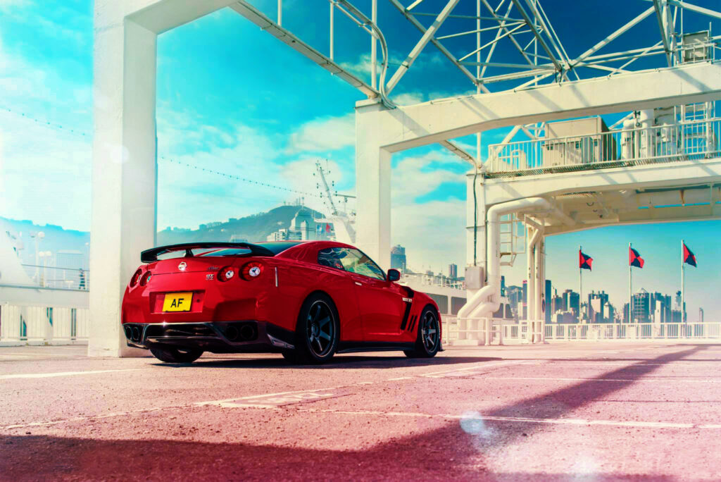Vibrant Red Nissan GT-R Under Modern Architecture - Stunning Wallpaper