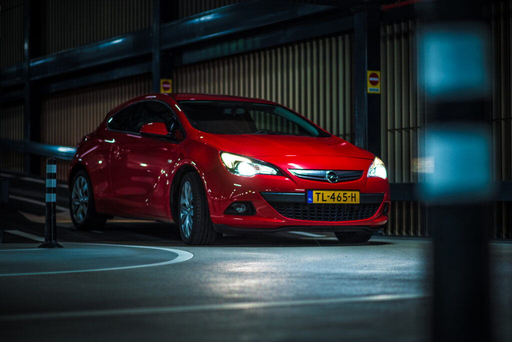 Vibrant Red Opel Astra in Dim Light: Sleek Design & Bright Headlights Wallpaper
