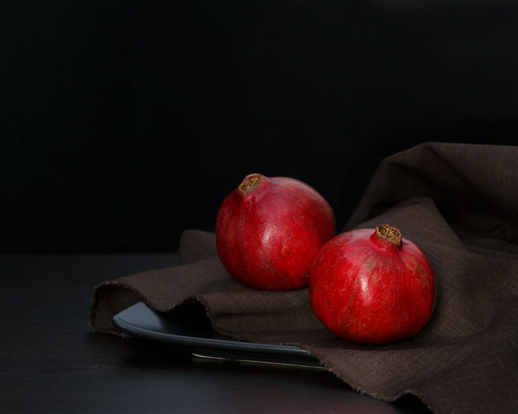 Elegant Wallpaper: Vibrant Red Pomegranates on Dark Plate