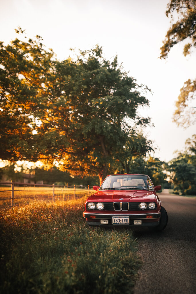Vibrant Red Retro BMW on Scenic Road at Sunset - Serene Wallpaper