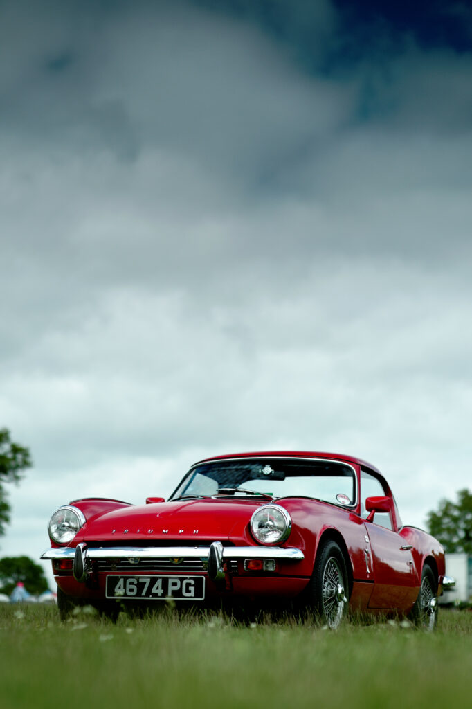 Vibrant Red Retro Car Wallpaper: Classic Design Against Cloudy Sky