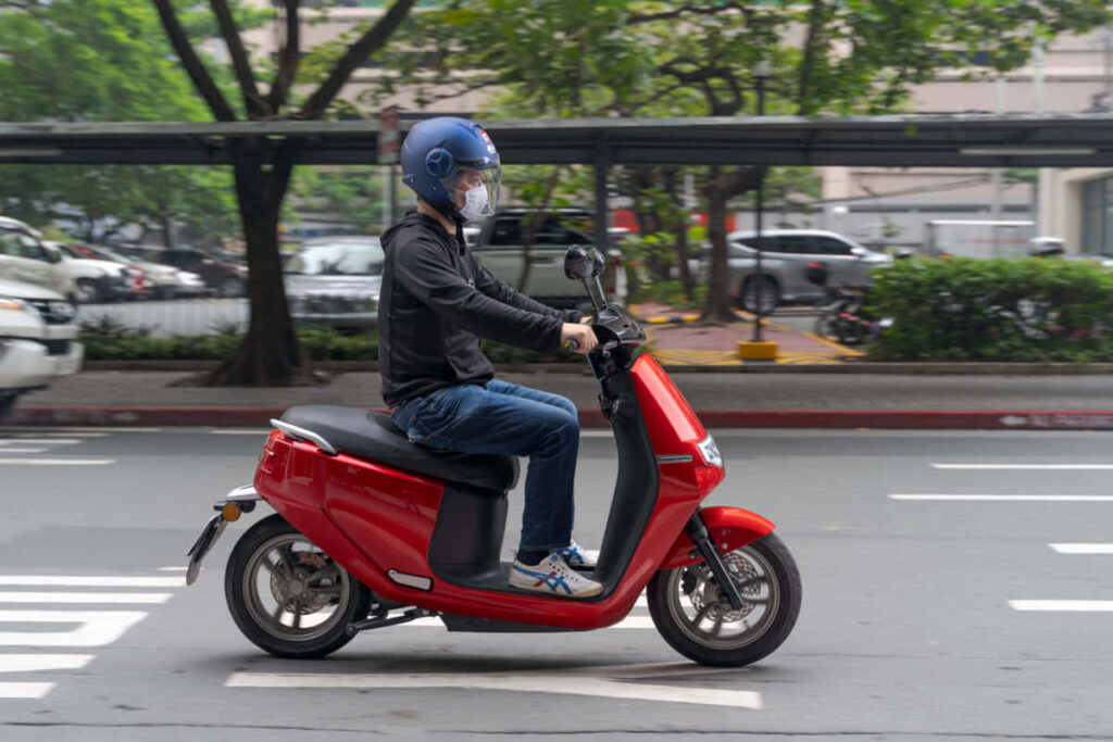 Vibrant Red Scooter Ride: Cityscape Wallpaper with Greenery & Cars
