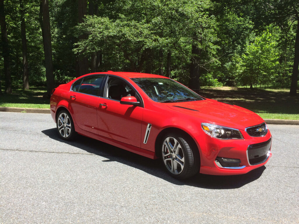 Vibrant Red Sedan in Lush Green Nature: Stunning Wallpaper Background